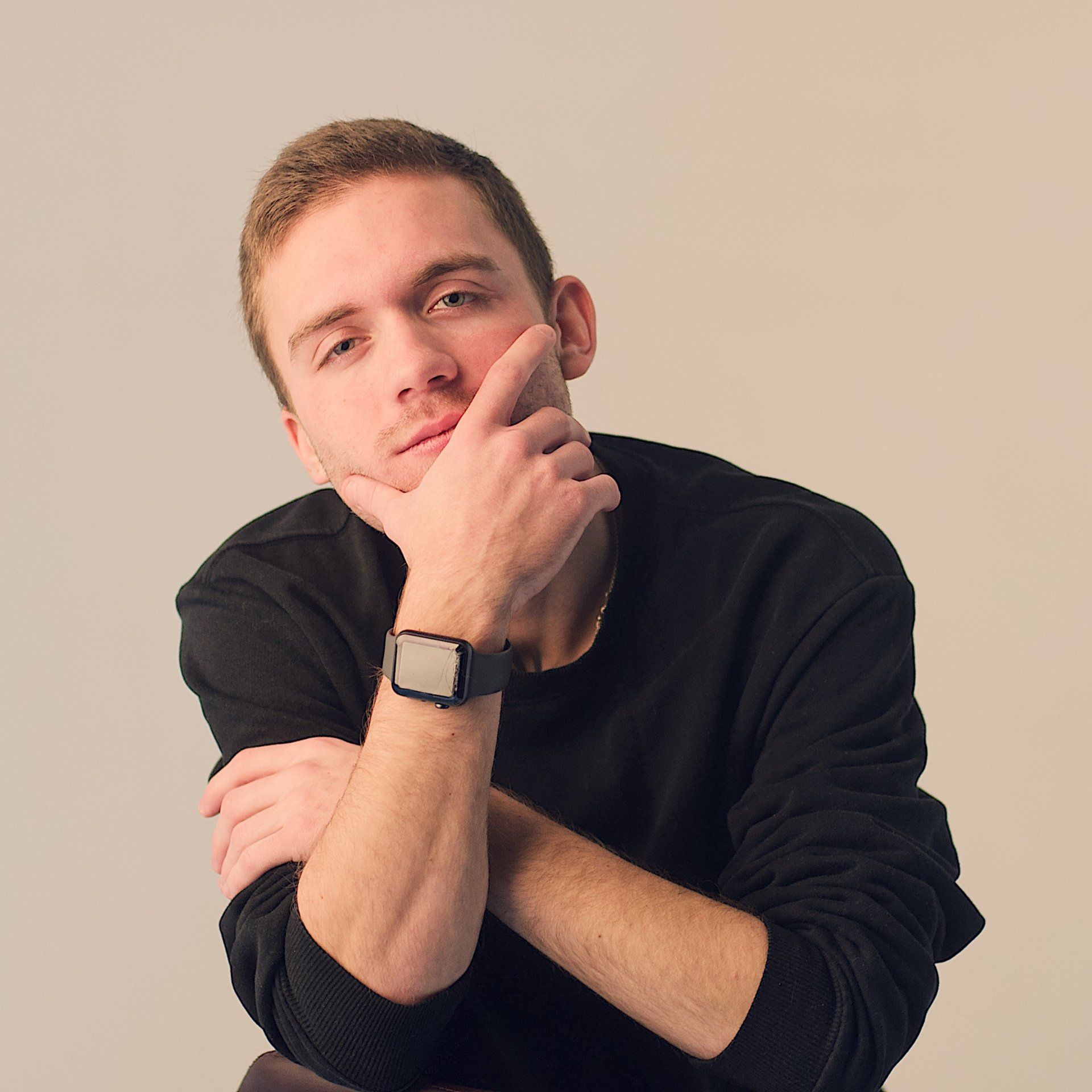 A man with his hand on his chin wearing a watch